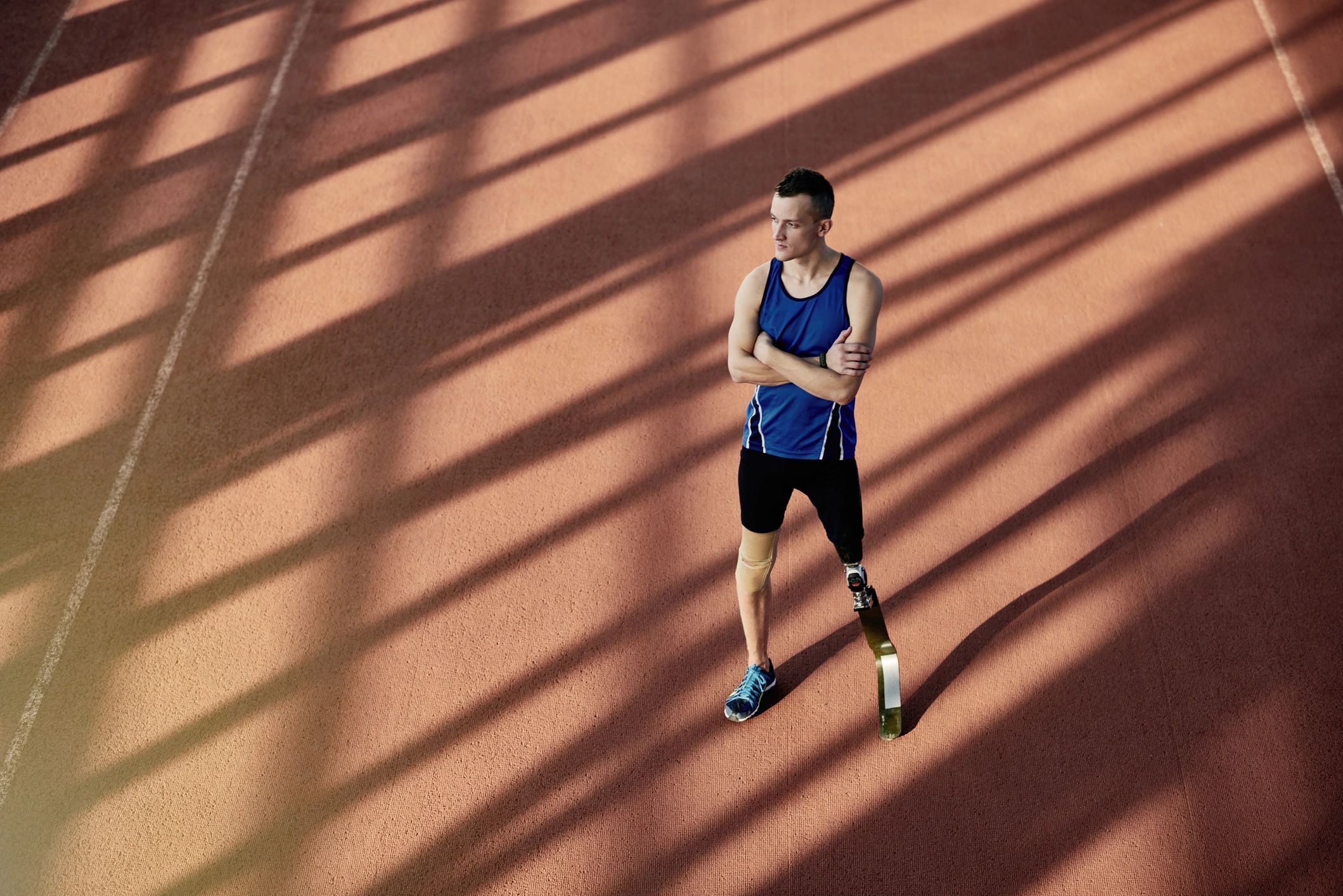 Athlete standing on a track in sunlight, representing recovery and resilience